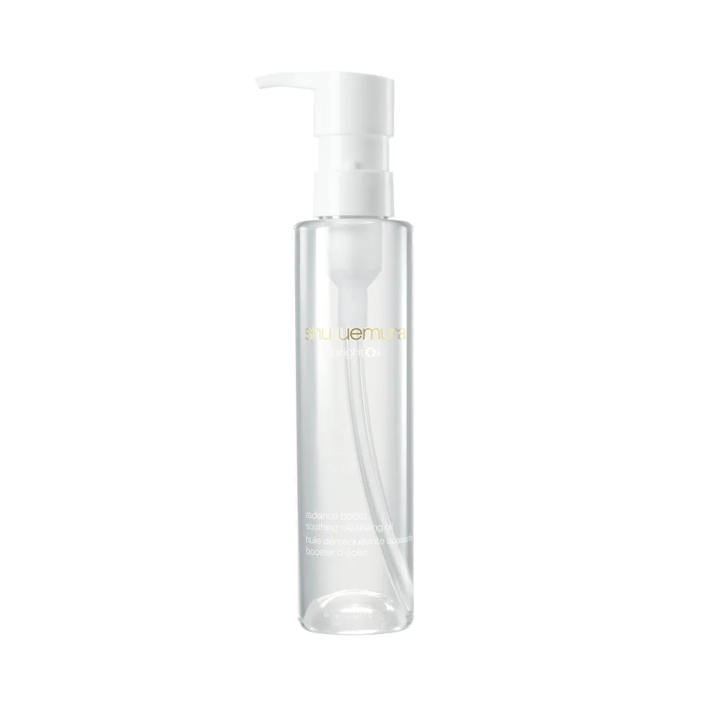 A clear, cylindrical plastic bottle of Shu Uemura Bright Oil cleansing oil stands upright against a plain white background, featuring a white pump dispenser at the top.
